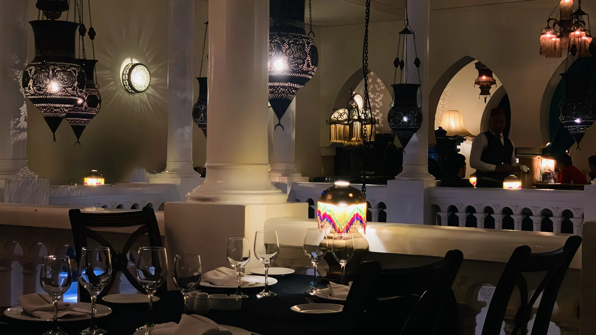 First floor balcony dining table with hanging Moroccan brass filigree lanterns and traditional server