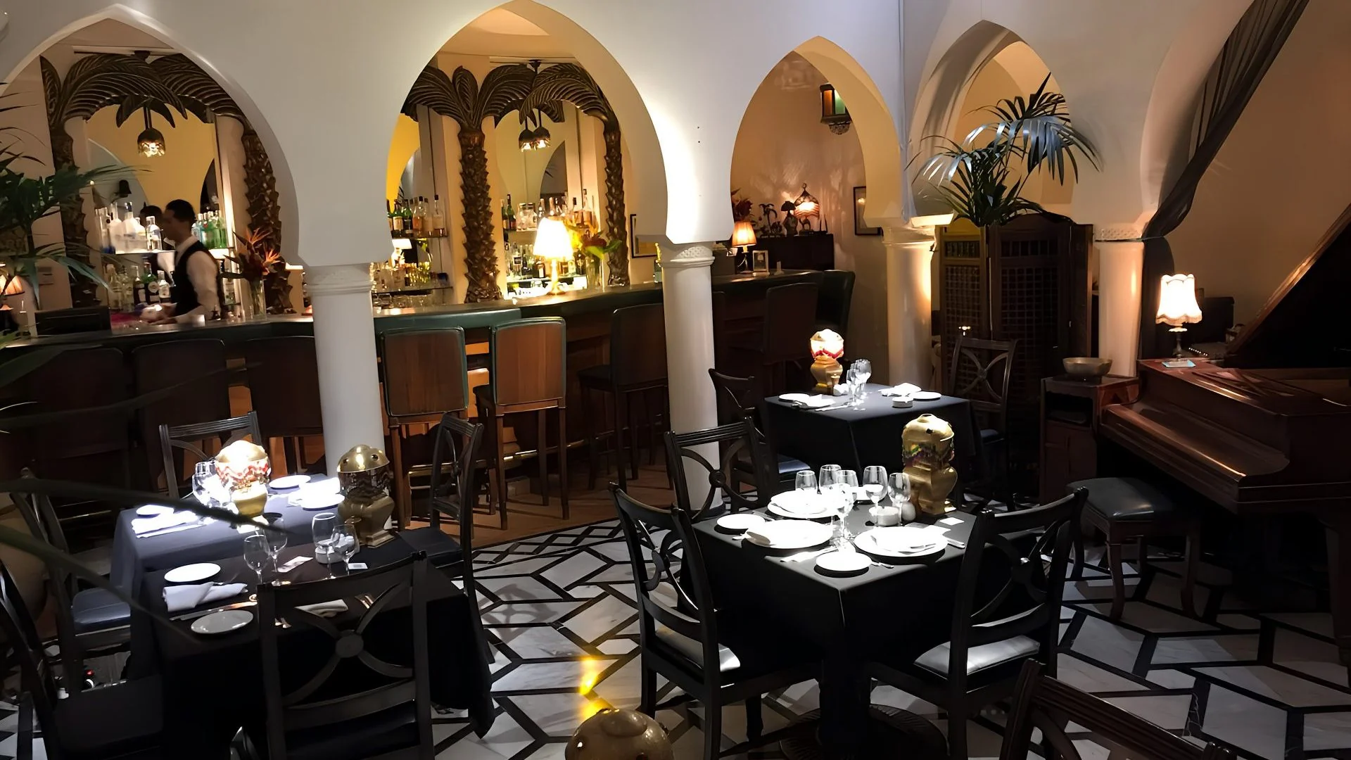 Rick's Café central dining hall, sculpted white arches, mahogany bar and grand piano
