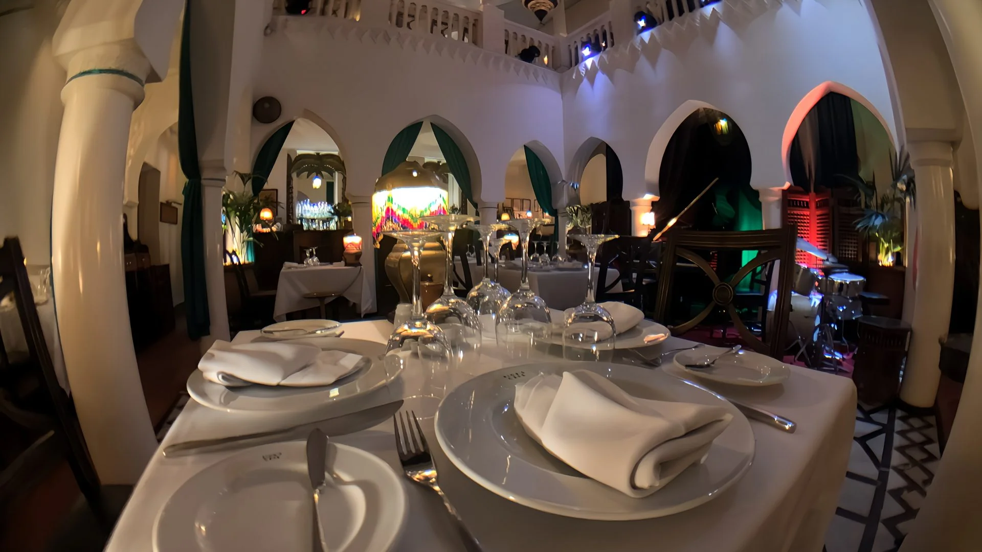 Impeccably dressed dining table in the central atrium with fine china, crystal glassware, and riad arches